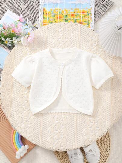 女童纯色针织短袖开衫，领口、袖口和下摆饰有精致蕾丝花边，穿孔设计，非常适合夏季海滩穿着
