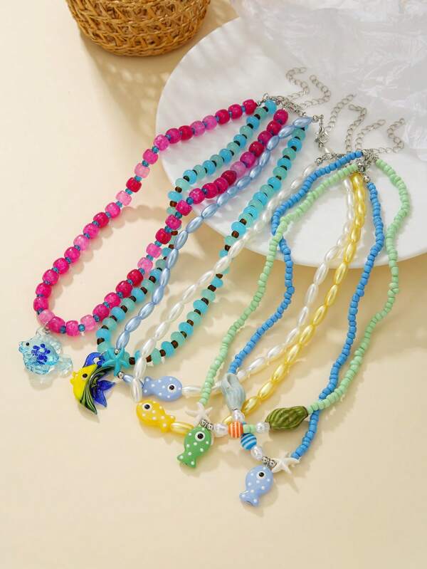 قلادة تتكون من 1 قطعة، بشكل موضوع البحر والاصطياف، من اللؤلؤ الصناعي، وخرز الراتنج المتشقق، وسمك خزفي صغير، وزجاج البحر بشكل سمكة استوائية، وجنمارين نجم البحر والأصداف، مناسبة للهدايا والارتداء اليومي