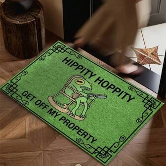 This Is A Floor Mat. The Base Color Is Green And There Are Black Decorative Patterns Along The Edges. The Middle Pattern Is A Frog Sitting In A Rocking Chair And Holding A Firearm. It Is Accompanied By The Text "HIPPITY HOPPITY GET OFF MY PROPERTY", Which Means "Jump And Jump, Leave My Territory".