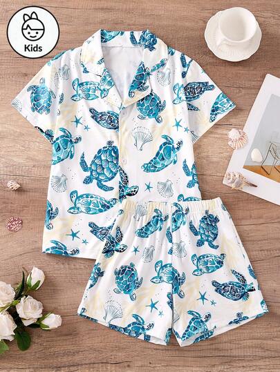 这款夏季女童睡衣套装包括一件白色短袖上衣和一条短裤，饰有蓝色海洋主题印花，图案包括海龟、海星和贝壳。非常适合居家休闲穿着。