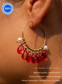 Un par de pendientes originales de perla. Estos pendientes exquisitamente diseñados presentan un aro dorado como Body principal. Enhebradas meticulosamente a lo largo del aro hay siete cuentas de cristal rojo natural con forma de gota. Acentuando estos, hay dos perlas barrocas, lo que crea un impresionante contraste con el ardiente atractivo de los cristales rojos.