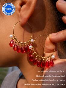 Un par de pendientes originales de perla. Estos pendientes exquisitamente diseñados presentan un aro dorado como Body principal. Enhebradas meticulosamente a lo largo del aro hay siete cuentas de cristal rojo natural con forma de gota. Acentuando estos, hay dos perlas barrocas, lo que crea un impresionante contraste con el ardiente atractivo de los cristales rojos.