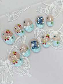 Coffret nail art comprend 10 ongles courts en amande faits main, avec un style French manucure bleu, des cerises peintes à la main et des strass carrés bleus, le tout pour un éclat brillant. Fabriqués selon le nouveau style Ballet Nail.