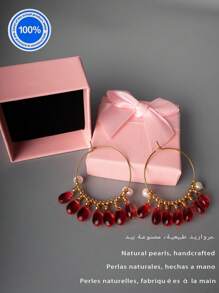 Un par de pendientes originales de perla. Estos pendientes exquisitamente diseñados presentan un aro dorado como Body principal. Enhebradas meticulosamente a lo largo del aro hay siete cuentas de cristal rojo natural con forma de gota. Acentuando estos, hay dos perlas barrocas, lo que crea un impresionante contraste con el ardiente atractivo de los cristales rojos.