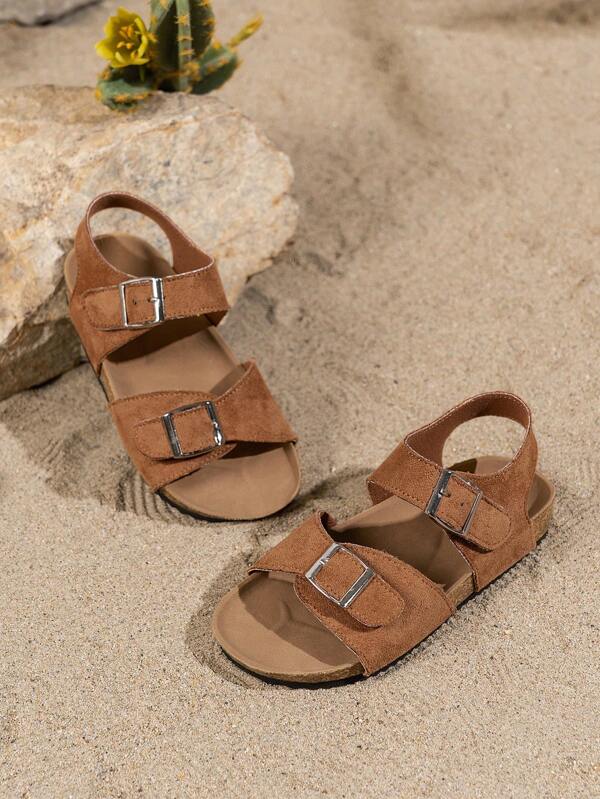Un par de sandalias antideslizantes de verano para niños. La parte superior está hecha de material rosa con dos correas y hebillas metálicas ajustables. La suela está parcialmente hecha de corcho con un exterior antideslizante de color negro. El estilo general es dulce y casual, adecuado para niñas de 3 a 12 años en el verano para viajes diarios, paseos y otras ocasiones, mostrando una elegancia suave y encantadora.