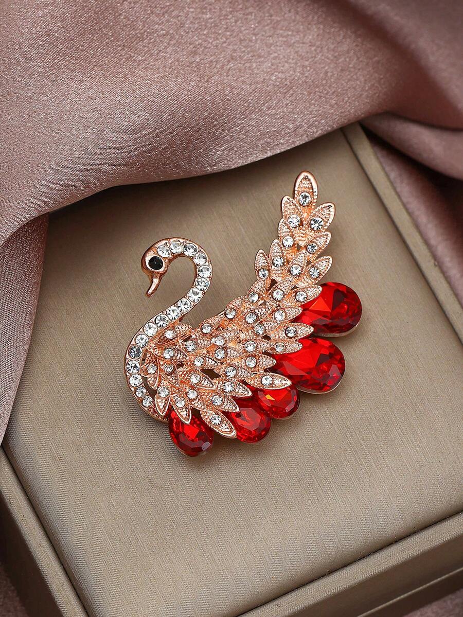 1枚优雅天鹅造型胸针，玫瑰金与红宝石交相辉映。精湛工艺展现细腻质感。天鹅象征着纯洁高贵，红宝石则增添了璀璨魅力，使其成为一件绝佳的时尚配饰。可用于服装配饰、衣服别针、包包饰物、背包饰物等。