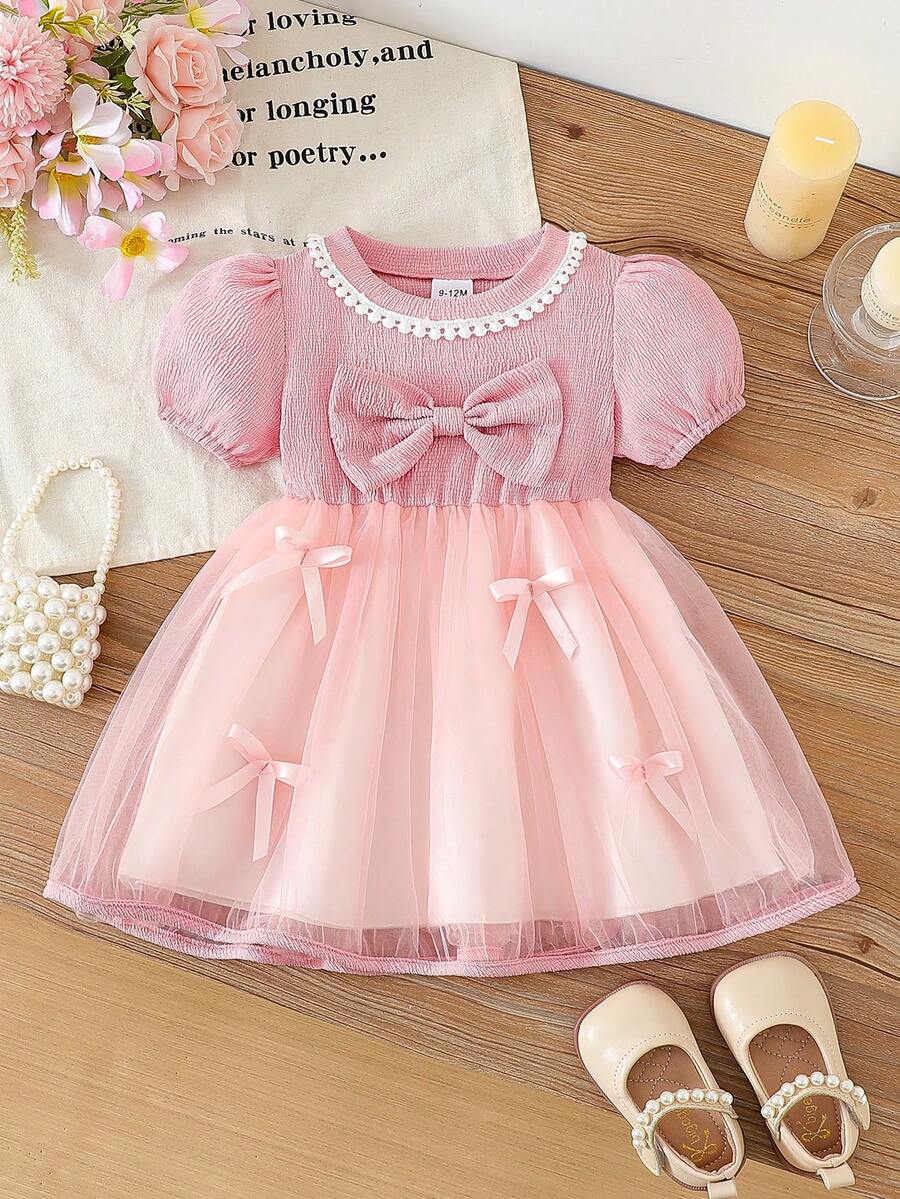 Ein süßes Sommerkleid in einem Stück für Baby Mädchen. Es hat rosa Puffärmel, kombiniert mit einer Spitzen-Rock-Borte und einer Schleife-Verzierung auf der Brust. Dieses Kleid ist geeignet für Neugeborene und Baby Mädchen von 0 bis 3 Jahren, um bequem im Sommer getragen zu werden. - Pink - Übersicht 1