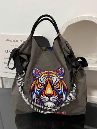1个新款休闲刺绣可爱老虎头图案轻便可折叠大容量尼龙手提包，配有可调节肩带，适合通勤、聚会等场合。