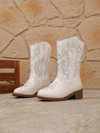 Ett par barn- och flickstövlar - Höga/mellanhöga westerncowboystövlar med spetsiga tår, dragkedjor i sidan och klackar, perfekta för fotograferingar och fester.