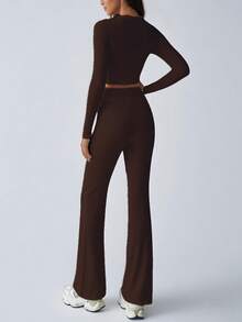 Completo sportivo da donna alla moda per l'autunno, top a maniche lunghe che scopre la pancia, pantaloni a zampa con lacci, aderente