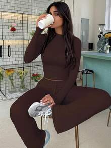 Completo sportivo da donna alla moda per l'autunno, top a maniche lunghe che scopre la pancia, pantaloni a zampa con lacci, aderente