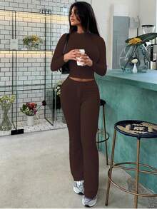 Completo sportivo da donna alla moda per l'autunno, top a maniche lunghe che scopre la pancia, pantaloni a zampa con lacci, aderente