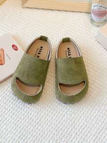 Este es un par de chanclas para niños con puntera. El estilo es de una sola pierna y el material de la parte superior parece ser de ante. La suela es gruesa. Este calzado unisex para niños pertenece a la edición coreana minimalista del verano de 2025.