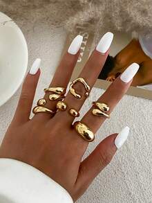 6pcs/Set Vintage Minimalist Alloy Molten Lava Teardrop Design Open Rings, Asymmetrical Fashionable Thick Metal Gold Tone Ring Set, Irregular Drops Of Liquid Metal Drape Over The Ring, Its Surface Replicating The Etched Texture Of Waves, With A Cold Sea Spray Luster On The Electroplated Silver Background. The Glazed Droplets Are Embedded With A Bubble Pattern, A Blue And White Gradient That Resembles The Crashing Waves Of The , And A Crescent-Shaped Indentation Hidden In The Ring's Opening And Closing Points. When The Fingertip Shakes, The Cut Surface Reflects The Shimmering Waves, As If Wearing The Instantly Frozen Waves On The Finger, The Gentle And Rigid Design Allows A Sense Of Niche And A Sense Of Art To Coexist.Suitable For Women's Daily Commute,Perfect Gift For Birthdays, Holiday Gifts, And Parties. Suitable For Daily Wear And Holiday Celebrations, Suitable For All Seasons, And Is An Ideal Choice For Holiday Accessories. - 金黃色 - 查看 3