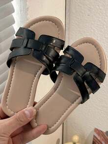 一双夏季热销儿童防滑拖鞋。鞋面为黑色，搭配简约交叉绑带设计，搭配浅棕色鞋垫，款式简约时尚。适合3-12岁女孩居家、室内外休闲活动等场景穿着，舒适百搭。