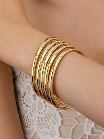 Cinq bracelets métalliques lisses dans un style circulaire, simple mais luxueux en or, convenant pour le port quotidien des femmes et les cadeaux pour les fêtes et les banquets