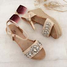 STYLEE FOOTWEAR Jute-Keilsandalen mit funkelnden Strasssteinen. Veredeln Sie Ihren Sommerlook mit diesem Design, das handwerklichen Stil und glamouröse Details vereint. Die mit Espartogras gefütterte Plateausohle bietet Komfort und Stabilität, während dekorative Steine einen eleganten Touch verleihen. Verstellbarer Schnallenverschluss für perfekten Sitz. Lieferung innerhalb von 1-3 Werktagen. Bohemian Strassperlen - Beige - Übersicht 1