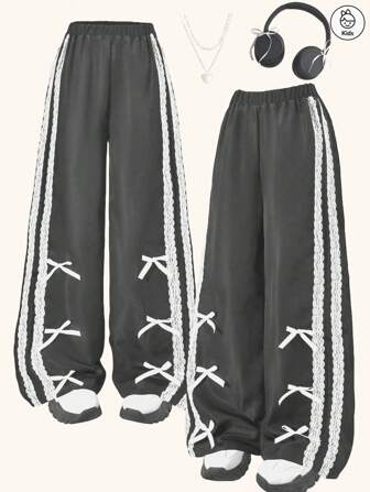 时尚女孩休闲黑色裤子，裤腿两侧有蕾丝织带和蝴蝶结装饰，适合春夏秋三季穿着，可用于春季郊游、户外活动、旅行和日常穿着，是送给女孩的绝佳礼物