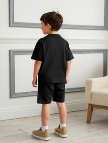 Conjunto para niño de 2 piezas con divertido estampado de chimpancé animado sosteniendo bananas y usando gafas de sol, inspirado en el popular meme italiano "Italian brainrots" con la frase "Chimpanzinni Bananini", que aporta un toque cómico, moderno y viral. Ideal para niños de 4 a 12 años. Disponible en colores verde, negro y gris. Incluye camiseta de manga corta y shorts con cintura elástica. Ropa infantil cómoda, fresca, urbana y a la moda. Perfecto para verano, días de juego, vacaciones o actividades al aire libre. - Negro - Ver 2