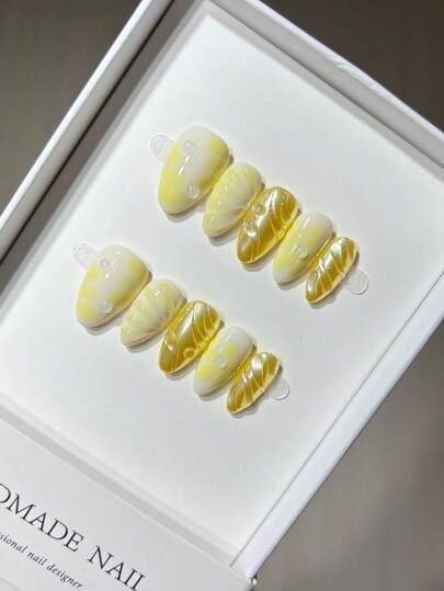 Uñas postizas con diseño de concha dorada y flor amarilla de forma almendrada y linda