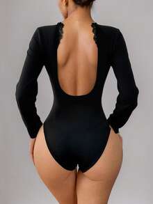 Un mono de unicolor con bordes de encaje en forma de V profunda y un mono ajustado con efecto moldeador del Body con una camiseta de manga larga. Un atuendo diario de alta gama y cómodo