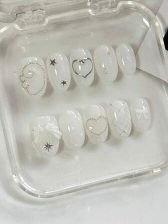 Cool And Sweet Summer Nail Art With 10 Short Oval-Shaped Pressed Nails. The Design Is Mainly In Pure And Transparent White. Silver Lines, Stars, Small Steel Beads, Etc. Are Decorated On The White Nails, Shining Brightly. There Are Also Three-Dimensional White Wings And A Cute Bow, Giving A Lovely And Elegant Appearance That Enhances The Beauty And Sophistication Of The Outfit. Can Be Reused. Nail Supplies Nails