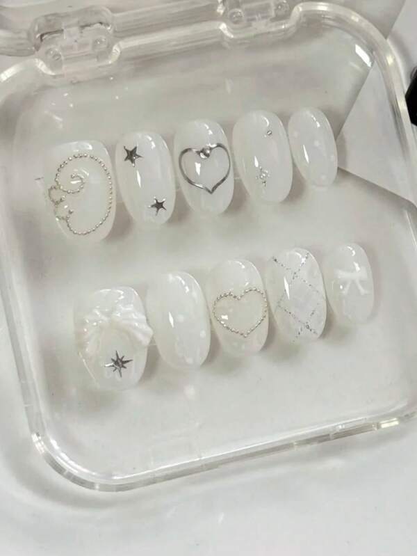 Cool And Sweet Summer Nail Art With 10 Short Oval-Shaped Pressed Nails. The Design Is Mainly In Pure And Transparent White. Silver Lines, Stars, Small Steel Beads, Etc. Are Decorated On The White Nails, Shining Brightly. There Are Also Three-Dimensional White Wings And A Cute Bow, Giving A Lovely And Elegant Appearance That Enhances The Beauty And Sophistication Of The Outfit. Can Be Reused. Nail Supplies Nails