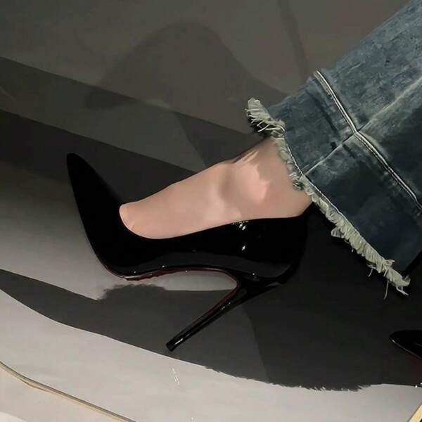 Schwarze High-Heel-Schuhe mit roter Sohle, Strassbesatz und spitzem Zehenteil aus lackiertem Leder, die eine selbstbewusste und attraktive Ausstrahlung haben