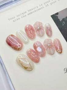 10 móng giả hình oval cỡ trung bình với tông màu hồng nude và trắng nhạt chủ đạo, cánh hoa 3D (đính ngọc trai), đường viền lá vàng, mảnh vỏ sò óng ánh tạo nên không gian lãng mạn và tinh tế, móng acrylic dán thủ công 100% có thể tái sử dụng dành cho nữ dùng hàng ngày hoặc dự tiệc. - Nhiều màu - Xem 13