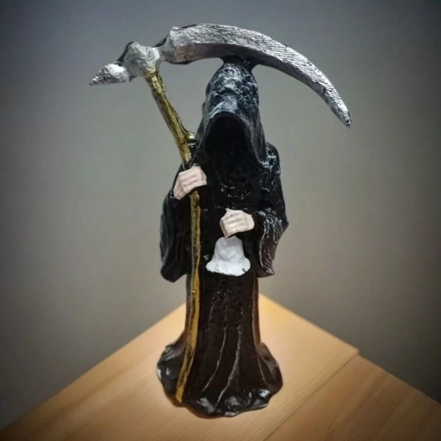 17 cm tall resin grim reaper statue holding a sickle and bell, dressed in a black hooded robe.