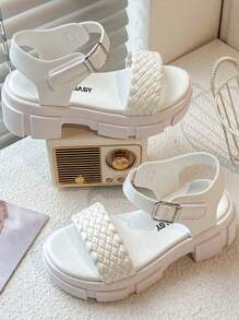 A Pair Of Children's/Girls' Sandals. The Main Body Of The Upper Is White. The Cross-Woven Straps Are In A Combination Of And Pink. There Is A Metal Buckle Strap At The Ankle.