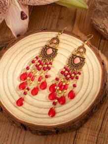 一对波西米亚风格的复古耳环，饰有雕刻图案和油滴细节，水滴形流苏由种子珠制成。适合女士在节日庆典期间佩戴。