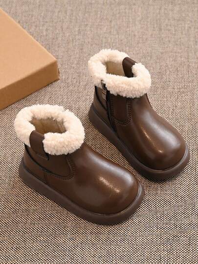 Un par de botas de tobillo acolchadas con hebilla para niños, adecuadas para el invierno