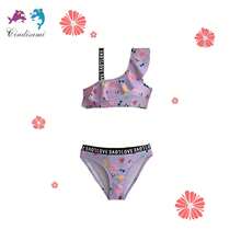 Conjunto de traje de baño de dos piezas para niñas de 6 a 12 años, una elección ideal para la playa en verano. Cuenta con un diseño de top sin mangas con tirantes tipo chaleco, presenta un escote redondo amplio con detalles de volantes plisados y un corte que revela la cintura, además de encantadores patrones infantiles. Fabricado con tela suave, su estilo combina lo casual con un toque de sensualidad, logrando que las niñas luzcan adorables, con un aire distinguido y atractivo, al mismo tiempo que se sientan completamente cómodas. Este conjunto de traje de baño de dos piezas es perfecto para disfrutar de los días en la playa con estilo y comodidad. - Morado - Ver 1