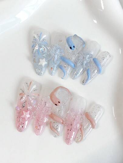 新年美甲套装。秋冬美甲。甜美梦幻的仙女风。十片装长款水滴形按压式假指甲。蓝色和粉色系，搭配闪耀的银色亮片、手绘烟花、五角星、蝴蝶结，以及手绘可爱的蓝粉色蛇。优雅甜美，精致细腻
