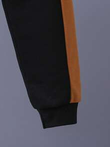 Ung pojke med bokstavstryck, färgblock och rund halsringning, tröja och mjukisbyxor, avslappnad outfit