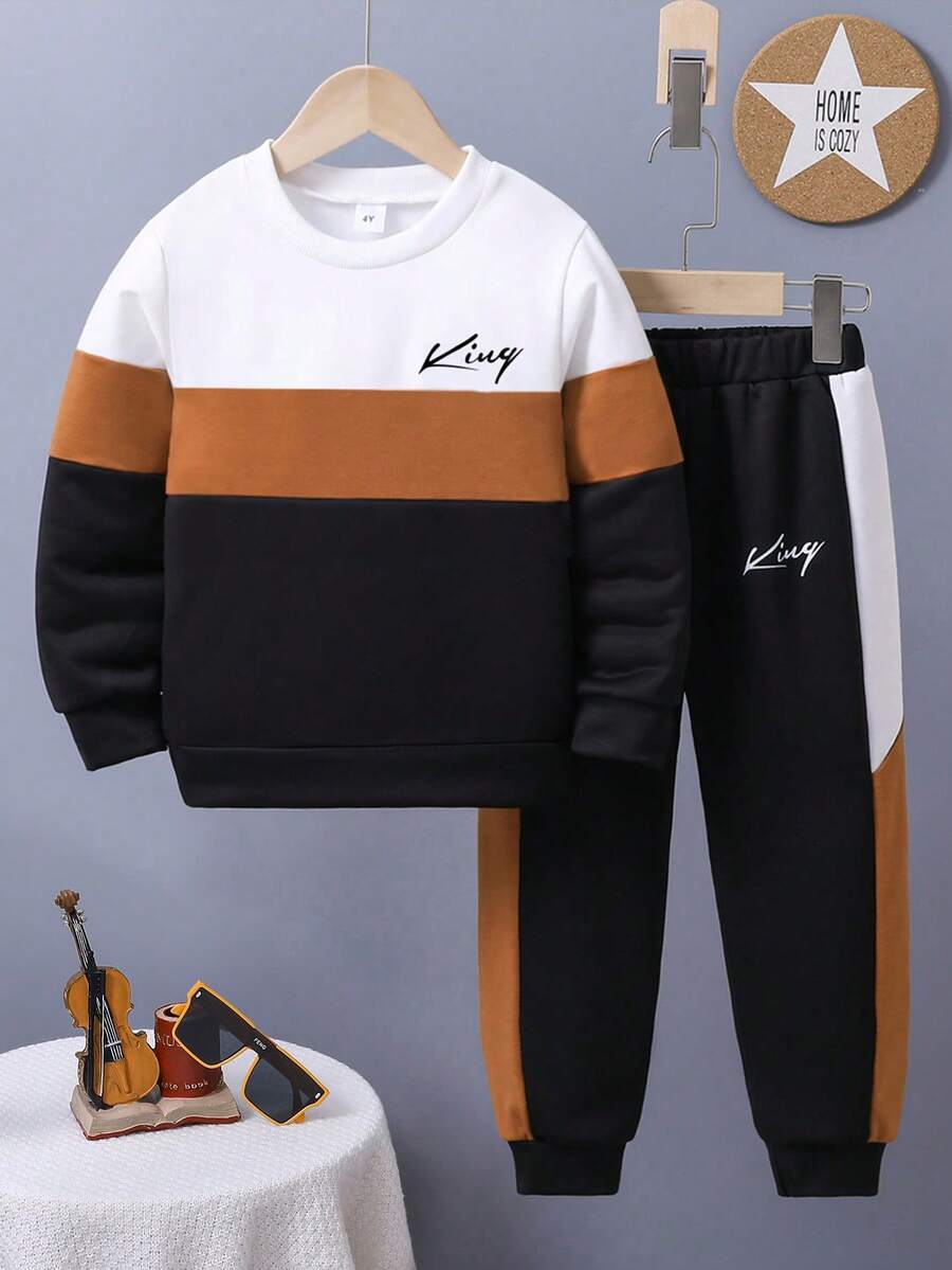 Ung pojke med bokstavstryck, färgblock och rund halsringning, tröja och mjukisbyxor, avslappnad outfit