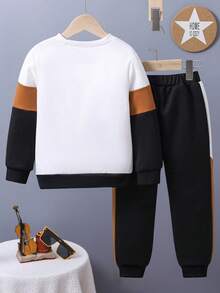 Ung pojke med bokstavstryck, färgblock och rund halsringning, tröja och mjukisbyxor, avslappnad outfit