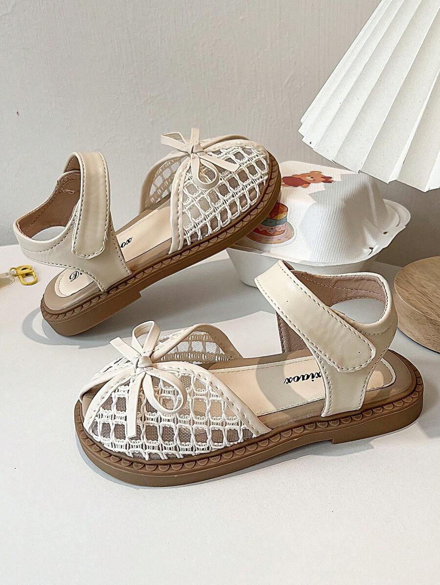A Pair Of Summer Girls' Sandals. The Upper Is Made Of Leather And White Lace, With A Bow At The Toe And A Hook And Loop Strap Design For Easy Putting On And Taking Off. The Brown Sole Is Decorated With Patterns. The Overall Style Is Sweet And Cute, Suitable For Daily Wear By Children Aged 3 To 12. - Beige - View 1