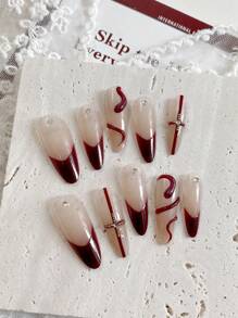 Neujahrsnägel. Mit einem süßen, kühlen, prächtigen und eleganten Stil sind dies handgefertigte 10 Stücke lange mandelförmige gepresste Fake-Nägel. Die Grundfarbe ist ein sanftes Nude-Rosa, mit handbemaltem weinrotem Französisch-Stil, roten Kreuzlinien, leicht luxuriösen Stahlperlen und Diamantdekorationen.