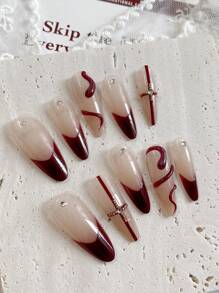 Neujahrsnägel. Mit einem süßen, kühlen, prächtigen und eleganten Stil sind dies handgefertigte 10 Stücke lange mandelförmige gepresste Fake-Nägel. Die Grundfarbe ist ein sanftes Nude-Rosa, mit handbemaltem weinrotem Französisch-Stil, roten Kreuzlinien, leicht luxuriösen Stahlperlen und Diamantdekorationen.