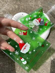 100 pièces Sacs d'emballage cadeaux verts OPP auto-scellants de 10 x 13 cm, avec motifs imprimés de Père Noël mignon et flocons de neige. Convient pour les faveurs et décorations de fête de Noël.