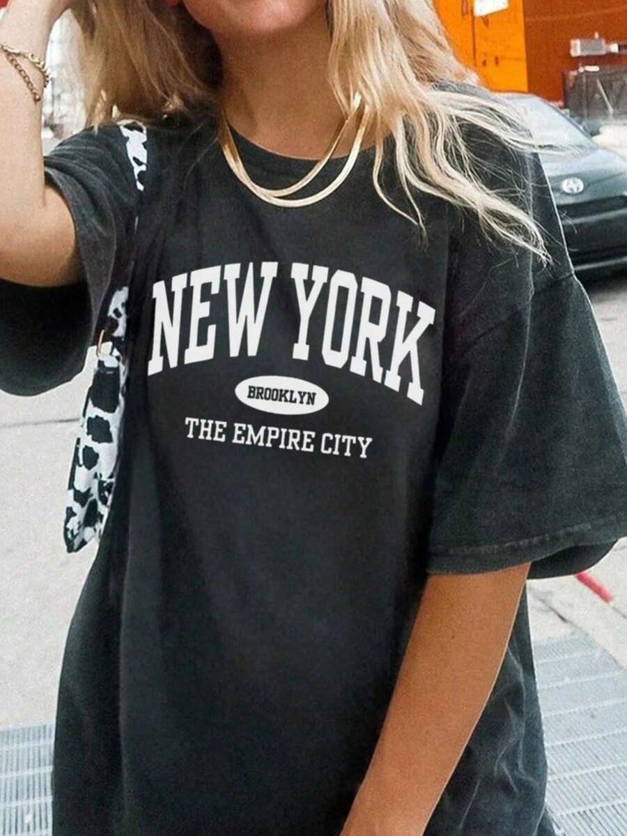 Camiseta casual de mujer de manga corta con cuello redondo y hombros descubiertos, con estampado de letras, para uso diario y versátil. Blusas gráficas de mujer en blanco, negro y rosa para outfits de vacaciones - Negro - Ver 1