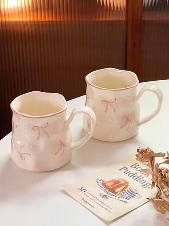 1/2件创意可爱陶瓷杯，手绘蝴蝶结图案，不对称杯身，办公休闲瓷茶杯，家用早餐杯，下午茶饮具，实用陶瓷器皿
