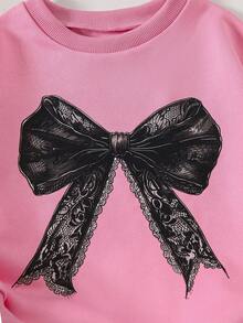 Conjunto de 2 piezas de sudadera rosa holgada con puños y bajo acanalados, cuello redondo, manga larga y estampado de lazo de encaje, emparejada con pantalones negros acampanados de cintura elástica, para niñas en otoño/invierno con estilo vintage y casual