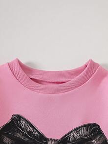 Conjunto de 2 piezas de sudadera rosa holgada con puños y bajo acanalados, cuello redondo, manga larga y estampado de lazo de encaje, emparejada con pantalones negros acampanados de cintura elástica, para niñas en otoño/invierno con estilo vintage y casual