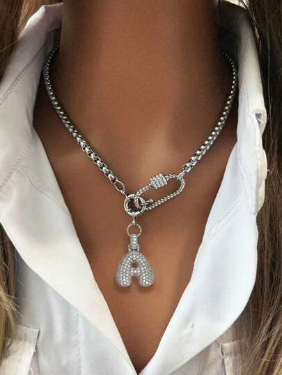 Este collar de mujer de oro presenta un colgante con letra 3D y un diseño de cierre ovalado retorcido, emitiendo un deslumbrante brillo metálico. Su estilo único, dulce pero fresco y encantador, puede manejar fácilmente el estilo callejero y los atuendos refinados. Ya sea para el viaje diario o las ocasiones de fiesta, te convertirá en el centro de atención.