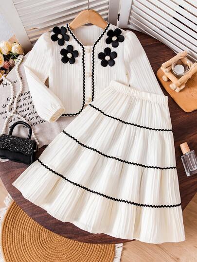 Young Girls Elegant Outfit - Short Puff Sleeve Top Paired With High-Waisted Skirt. The Puff Sleeve Design On The Top Is Playful And Cute, Flattering The Arm Line. The Multi-Layer Skirt Sways Gracefully When Moving. The White Main Color Is Fresh And Refined, With Delicate Black Lace And Floral Accents, And Faux Pearl Elements Adding An Elegant And Sophisticated Touch.