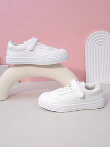 زوج من أحذية رياضية بيضاء بسيطة ذات لون أحادي من مواد ناعمة وقابلة للتنفس بأصابع مستديرة وكعب منخفض للاستخدام اليومي والمدرسة