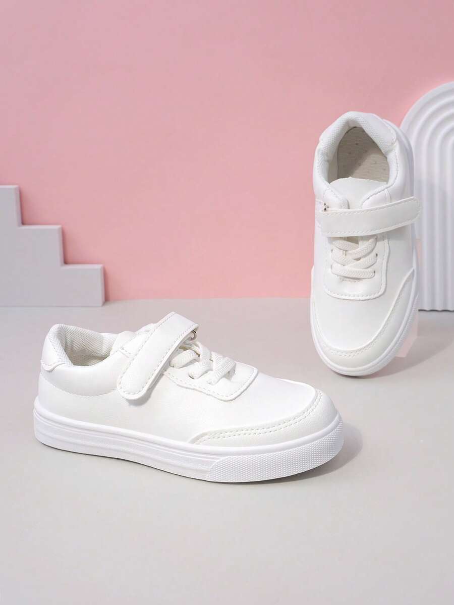 زوج من أحذية رياضية بيضاء بسيطة ذات لون أحادي من مواد ناعمة وقابلة للتنفس بأصابع مستديرة وكعب منخفض للاستخدام اليومي والمدرسة